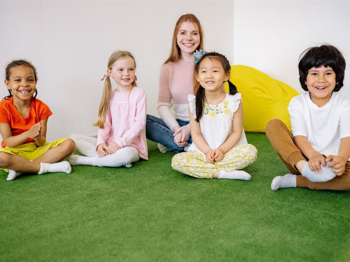 A teacher and a group of smiling children sitting together in a Sunnydale classroom